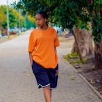 A young woman in an orange shirt and shorts